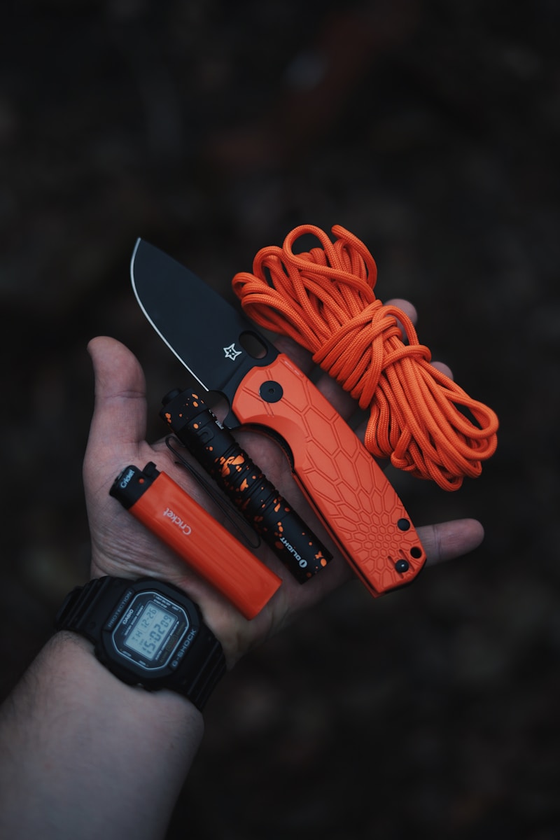 A person holding a knife and orange cord